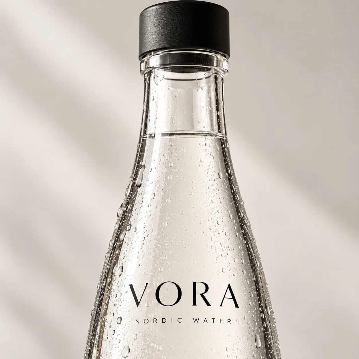 VORA-flaskens sorte kapsel, klare glas og diskrete logo med fine kondensdråber